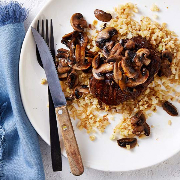 Plate of steak and mushrooms on top of fried rice