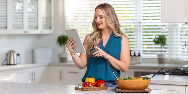 Young mother in spacious kitchen cooking and checking the recipe on a tablet computer