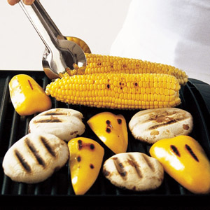 corn cobs, mushrooms and pieces of yellow capsicum on a barbecue