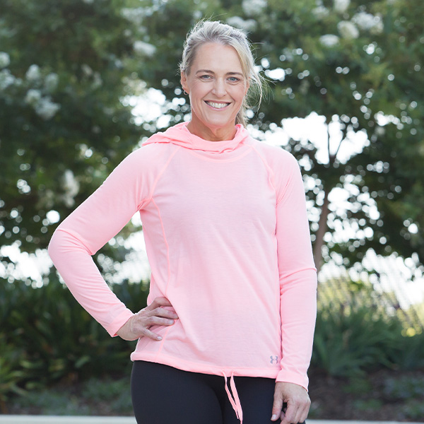 Portrait of member Sarah in a pink exercise jumper and tight black pants