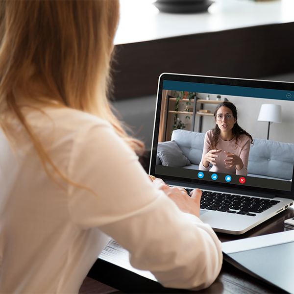 Over the shoulder shot of woman talking to another woman through a laptop computer